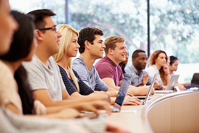 Studenten sitzen auf Ihren Plätzen und hören zu 