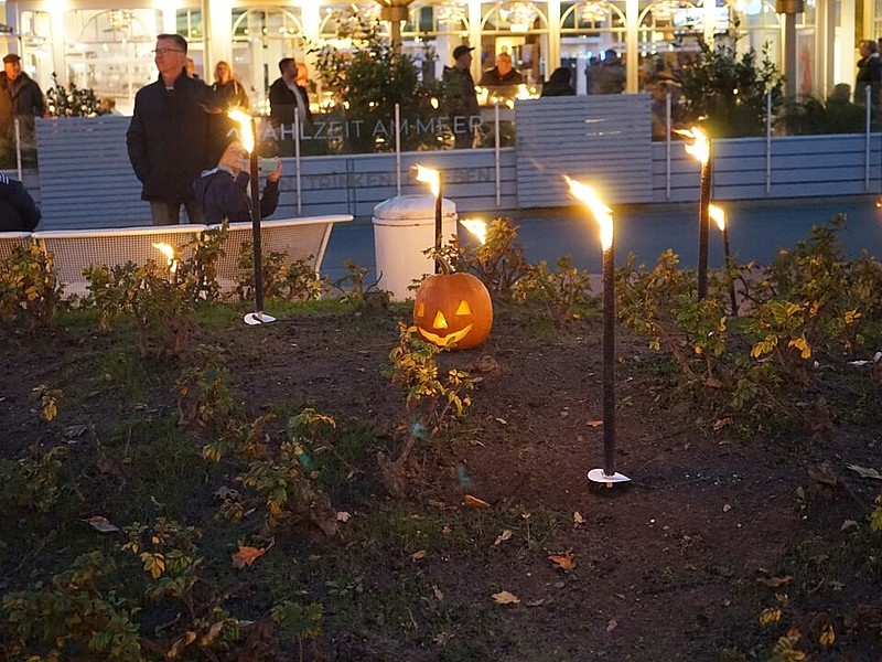 Das Bild stammt von der Veranstaltung Duhnen im Kerzenschein und zeigt leuchtende Fackeln mit einem geschnitzten Kürbis in der Mitte. 