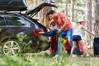 Familie räumt die Koffer aus dem Kofferraum