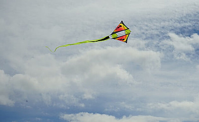 ein bunter Lenkdrache fliegt am wolkigen Himmel