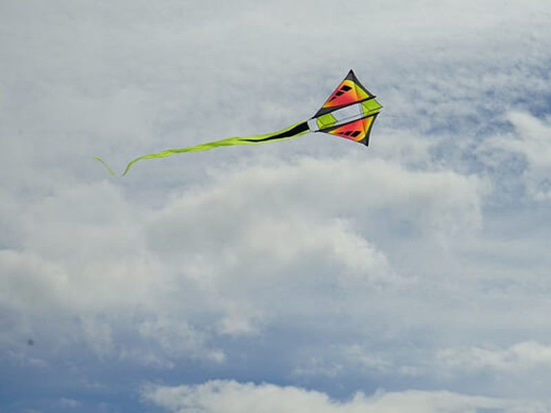 ein bunter Lenkdrache fliegt am wolkigen Himmel