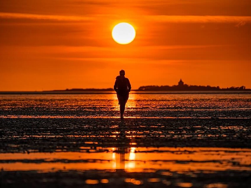 Person spaziert bei Sonnenuntergang Richtung Neuwerk