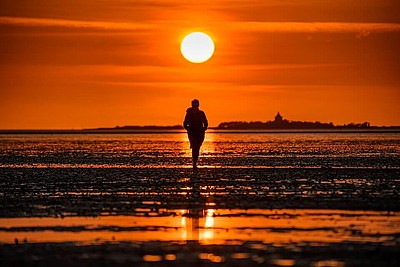 Person spaziert bei Sonnenuntergang Richtung Neuwerk