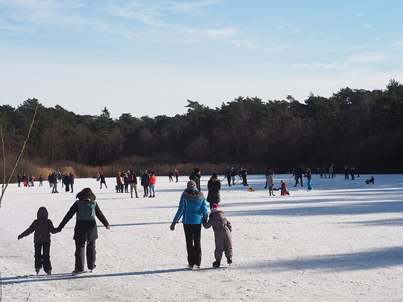 Familien laufen Schlittschuh auf einem zugefrorenen See im Wald in Cuxhaven