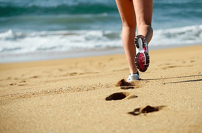 Beine einer Person, die am Strand läuft