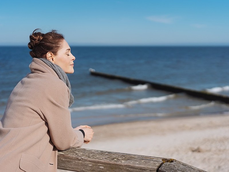 Frau steht an einem Geländer am Meer