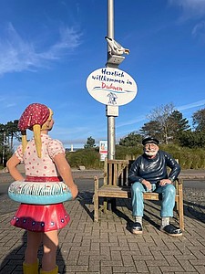 Kuddel am Duhner Kreisel mit einem Schild auf dem Willkommen in Duhnen steht.