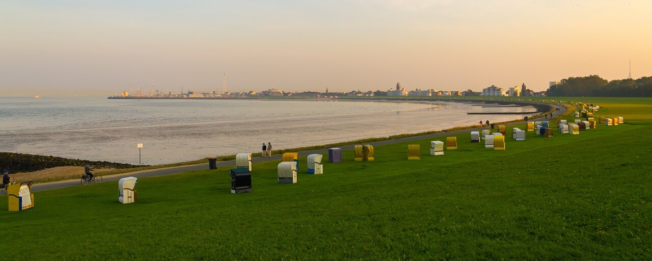 Blick von einer Ferienwohnung Döse auf die Strandkörbe in der Grimmershörnbucht bei Sonnenuntergang 