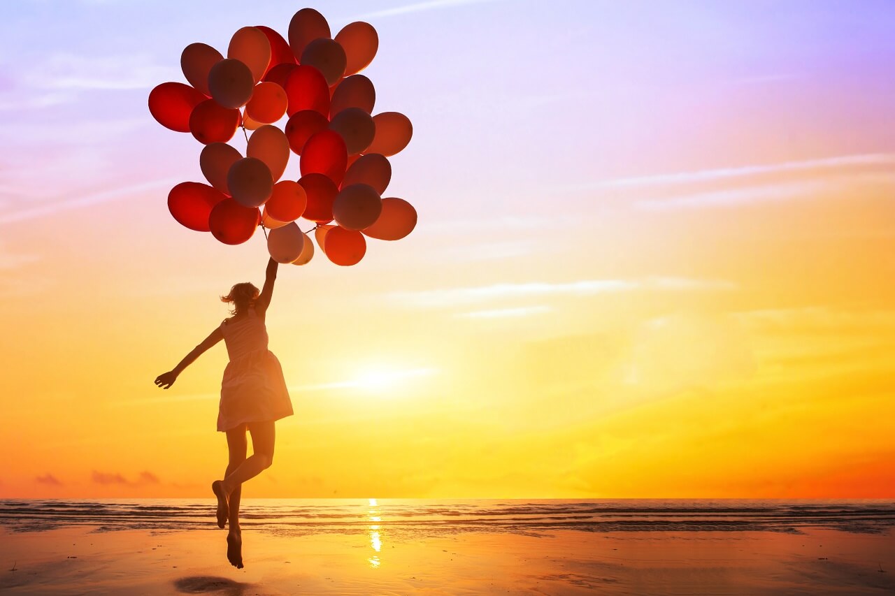 Mädchen hält Luftballons in den Himmel über dem Wattenmeer bei Sonnenuntergang