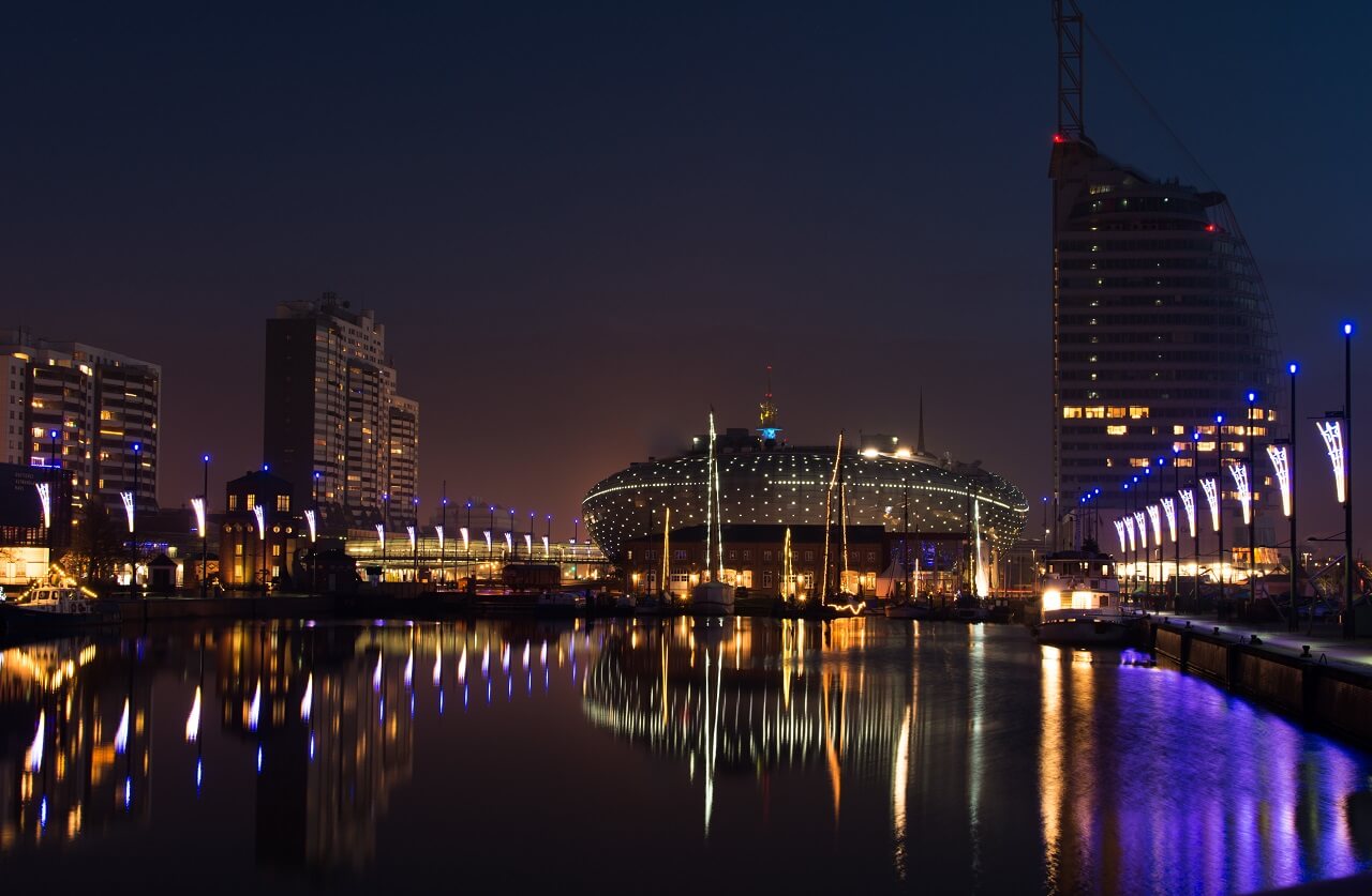Blick auf das beleuchtete Klimahaus, Sail City Hotel und den Hafen von Bremerhaven bei Nacht