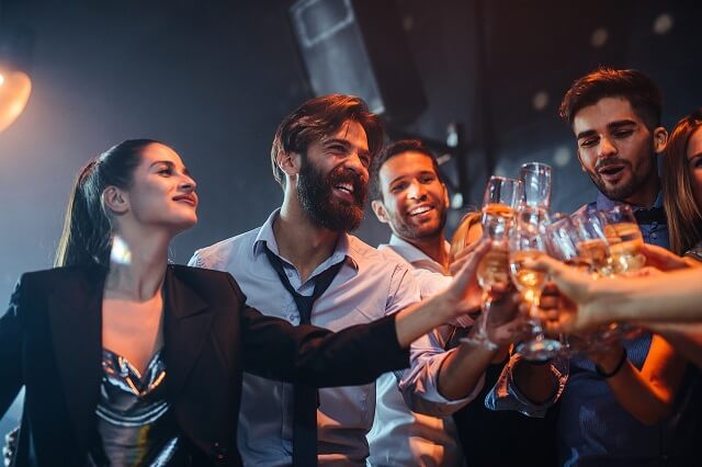 Personen stoßen in einer Bar mit Getränken an