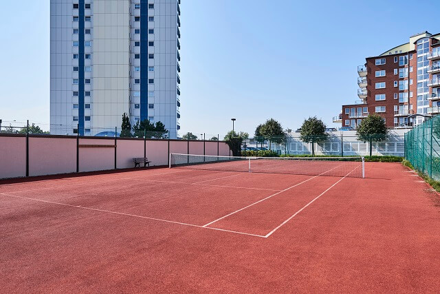 Im Vordergrund der Tennisplatz am Haus Frische Brise, welches im Hintergrund ist