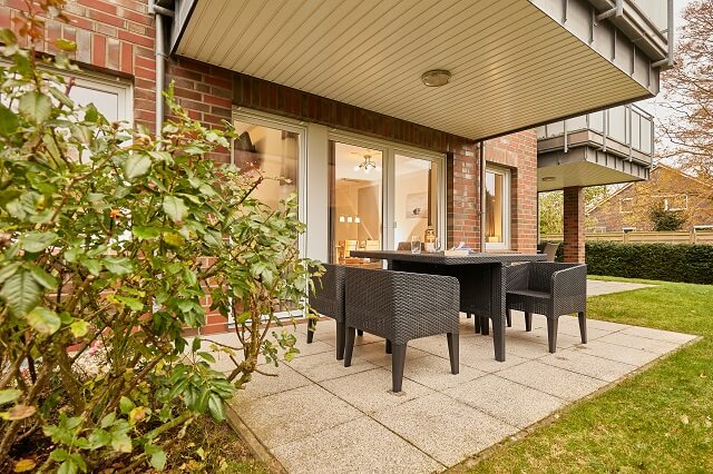 Blick vom Garten in die Wohnung und auf die Terrasse mit Gartenmöbeln