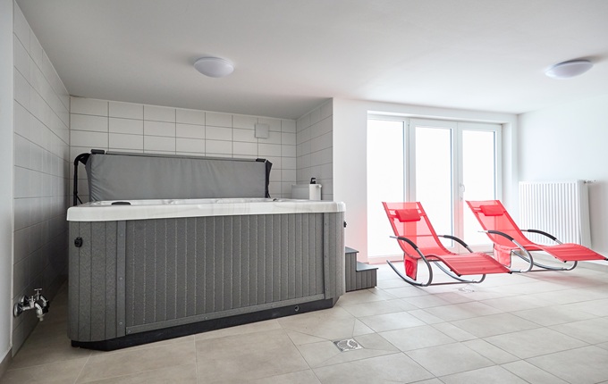 Blick in den Ruhebereich mit 2 roten Liegen und den Whirlpool im Haus NorthSide I