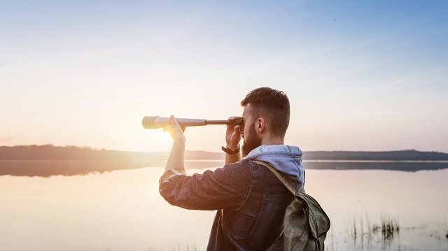 Mann mit Fernglas beobachtet Vögel auf dem Wasser