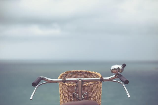 Blick auf den Fahrradlenker und Fahrradkorb eines Fahrrads am Wasser